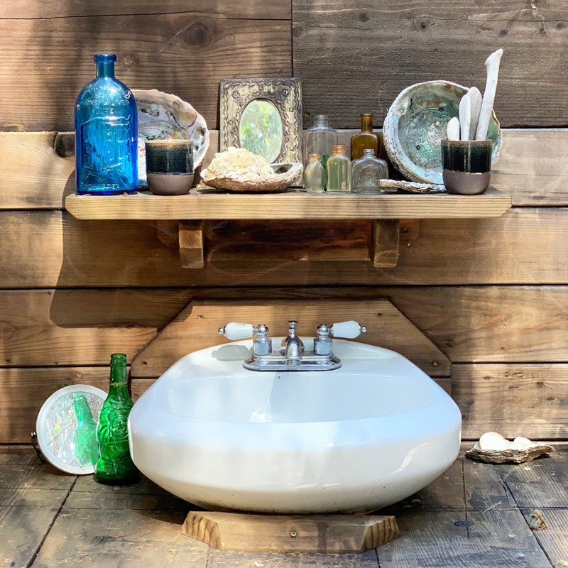 found objects on a shelf above an outdoor sink sink